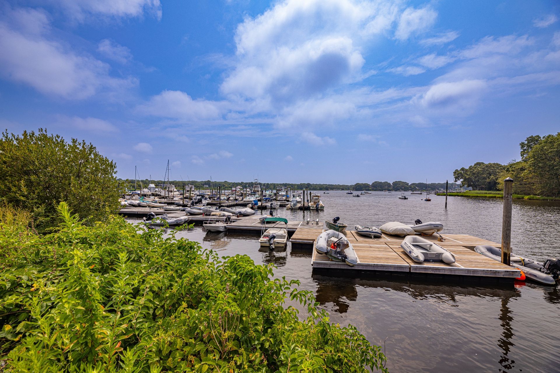 A dock filled with boats on a lake on a sunny day.