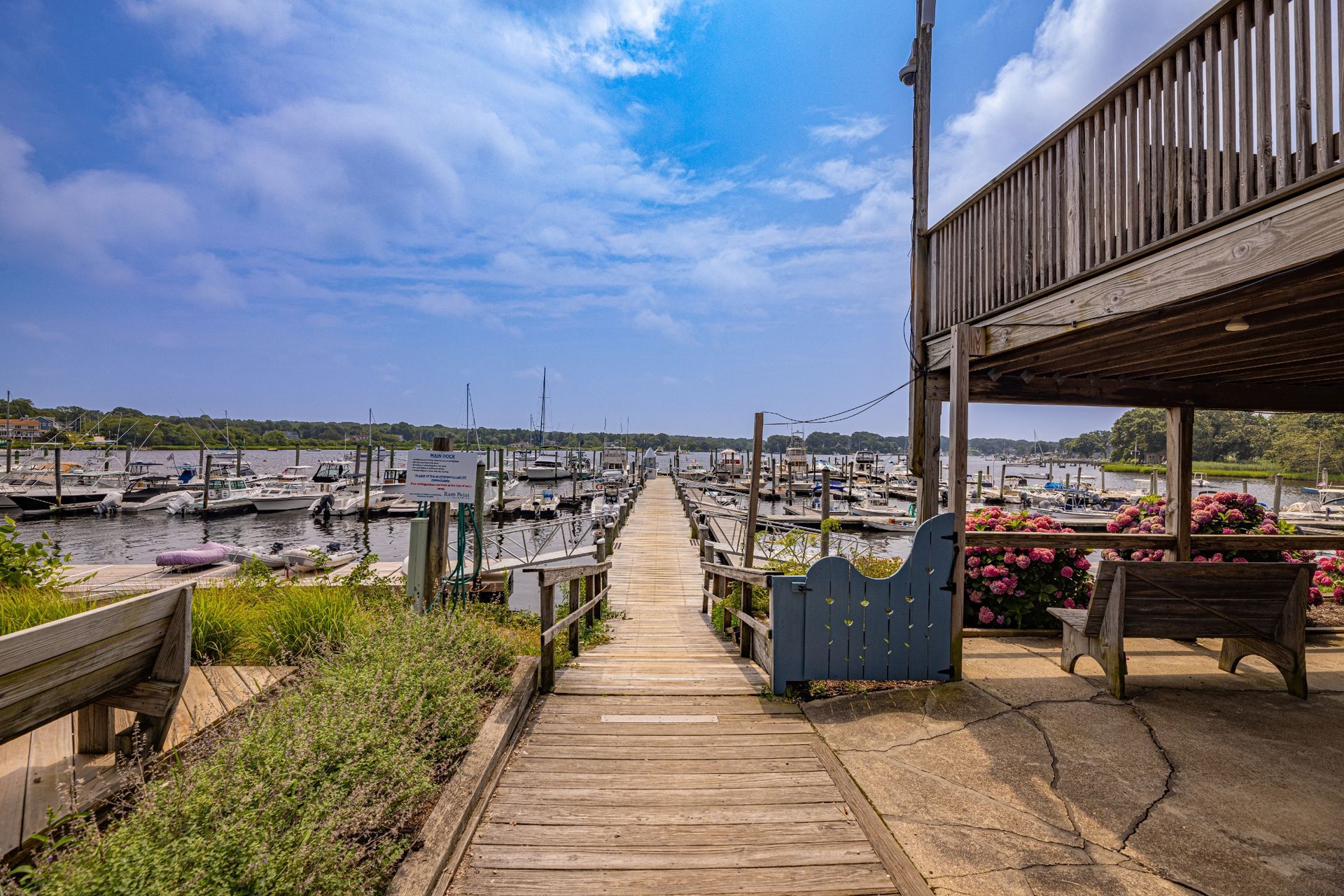 A wooden dock leading to a marina with boats docked.