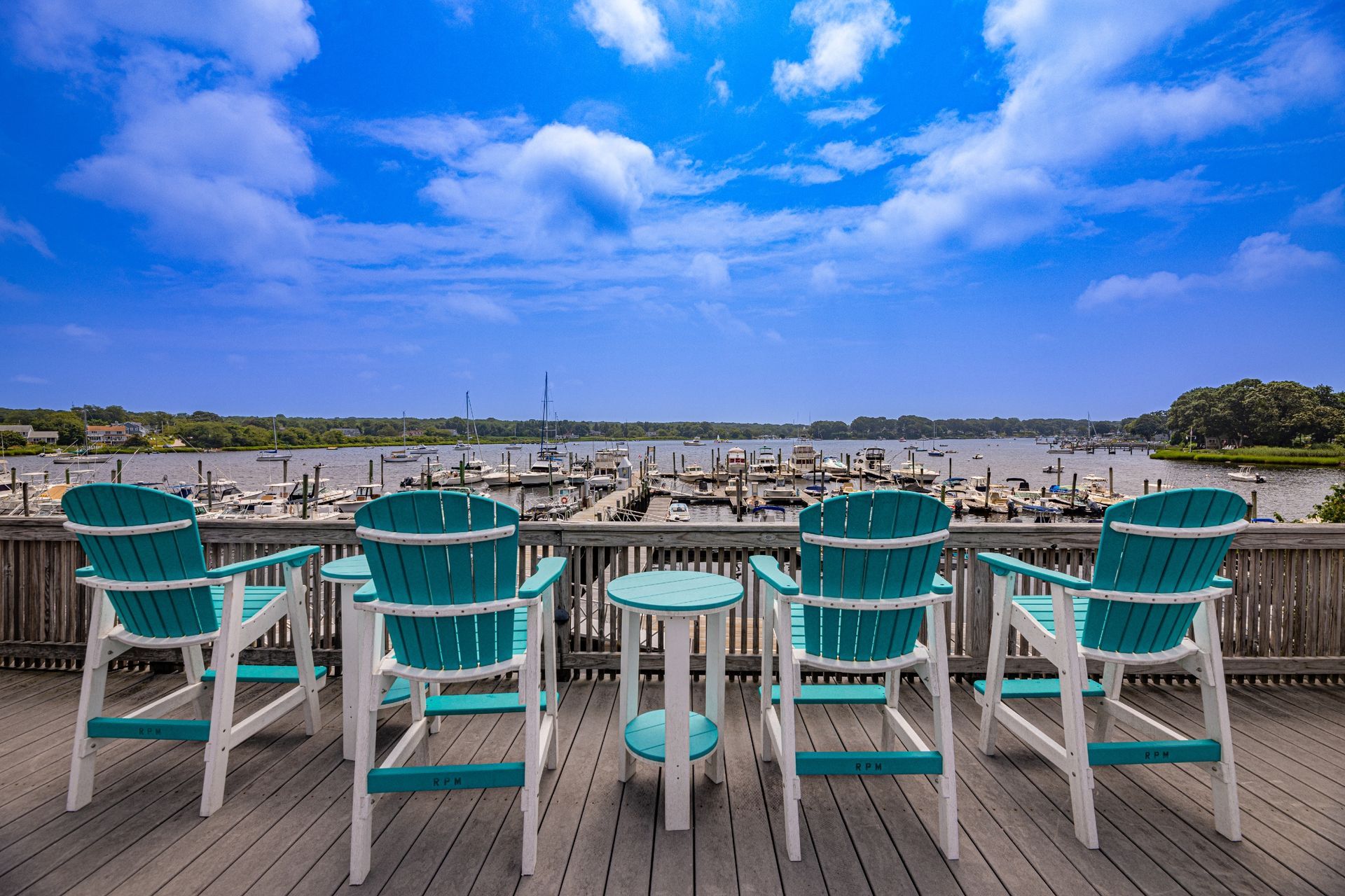 A group of chairs and a table on a deck overlooking a body of water.