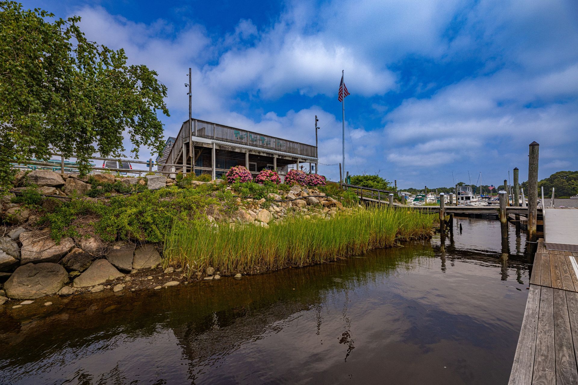 A river with a house in the background and a dock in the foreground.