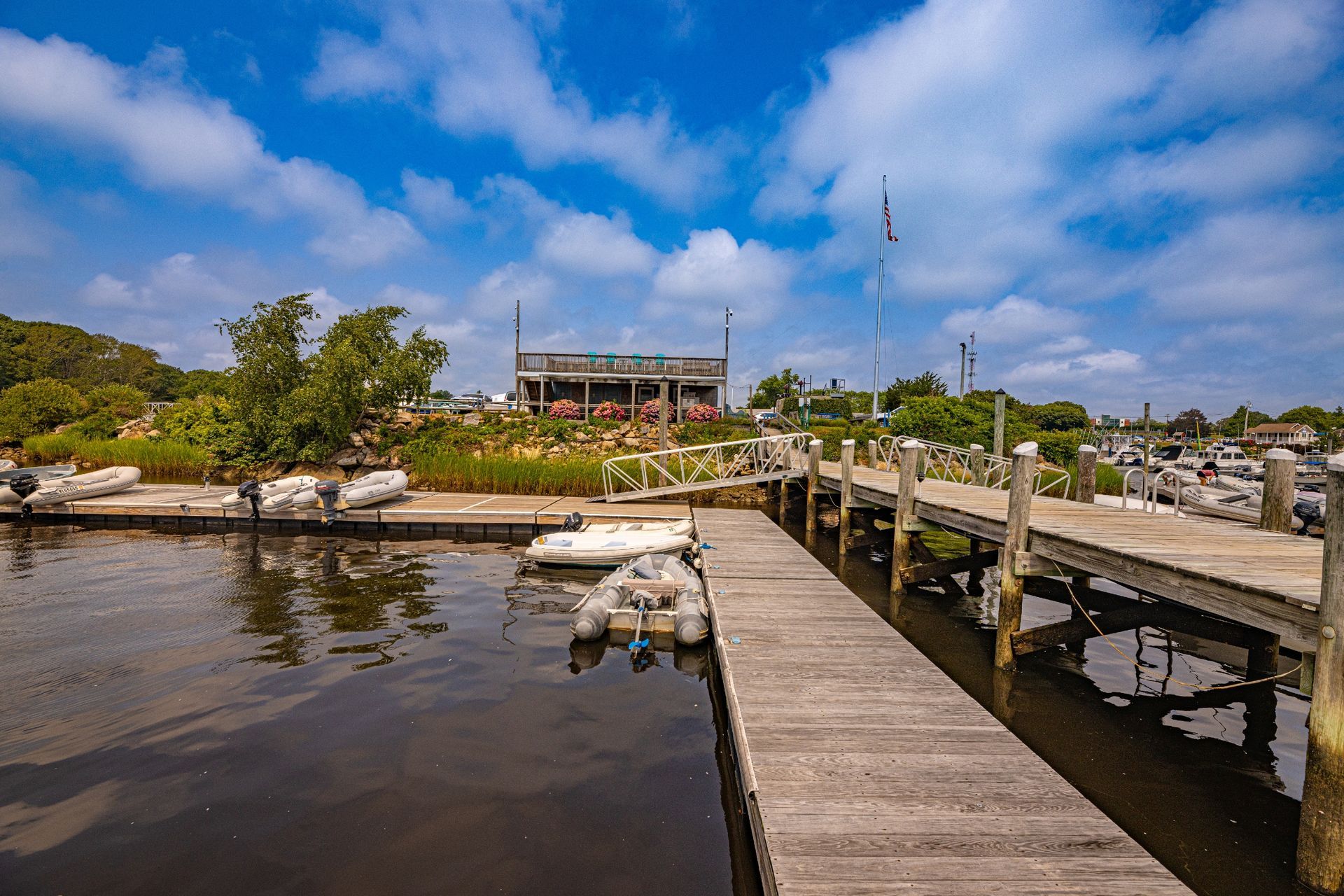 A dock with boats docked on it and a house in the background.
