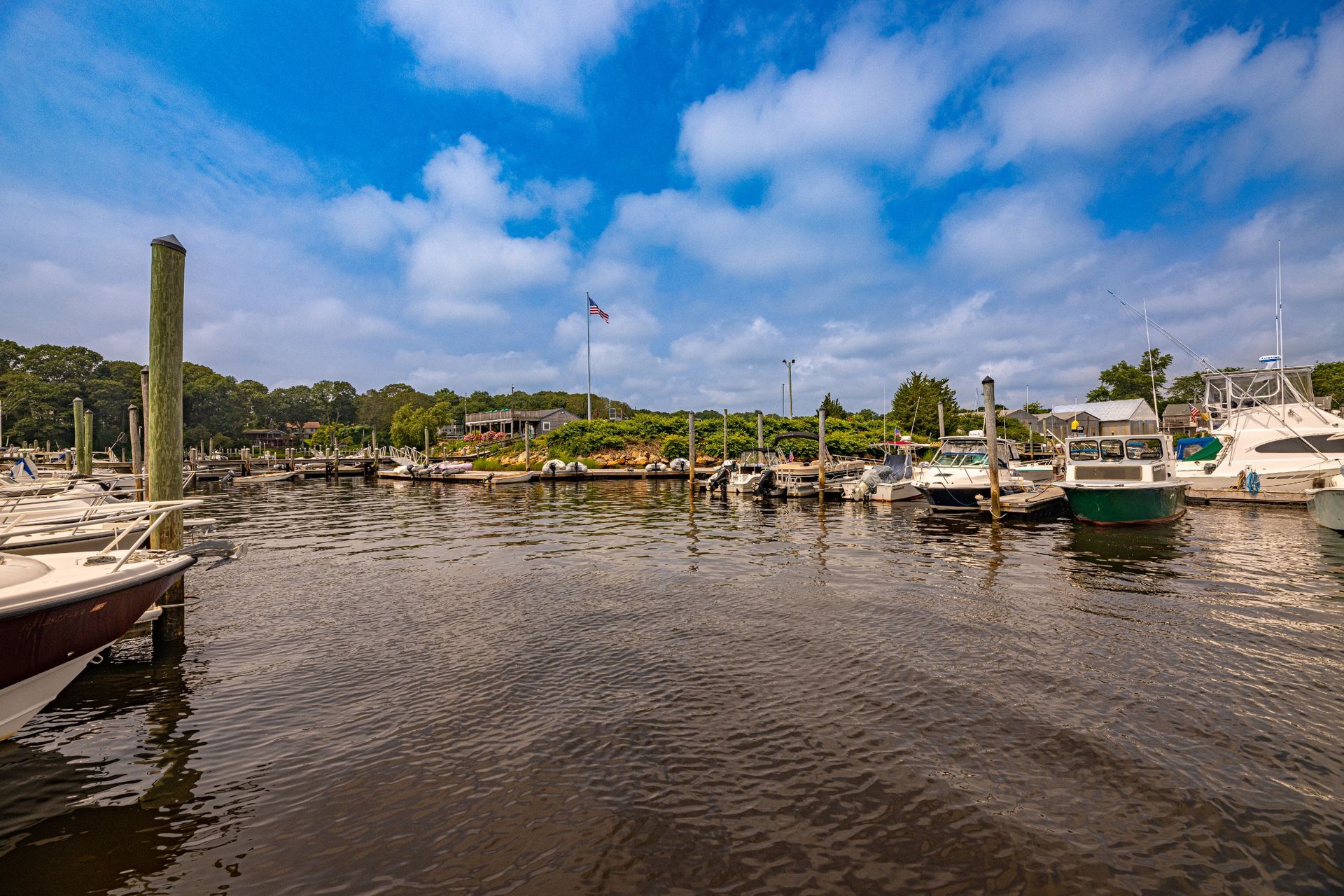A row of boats are docked in a marina on a sunny day.