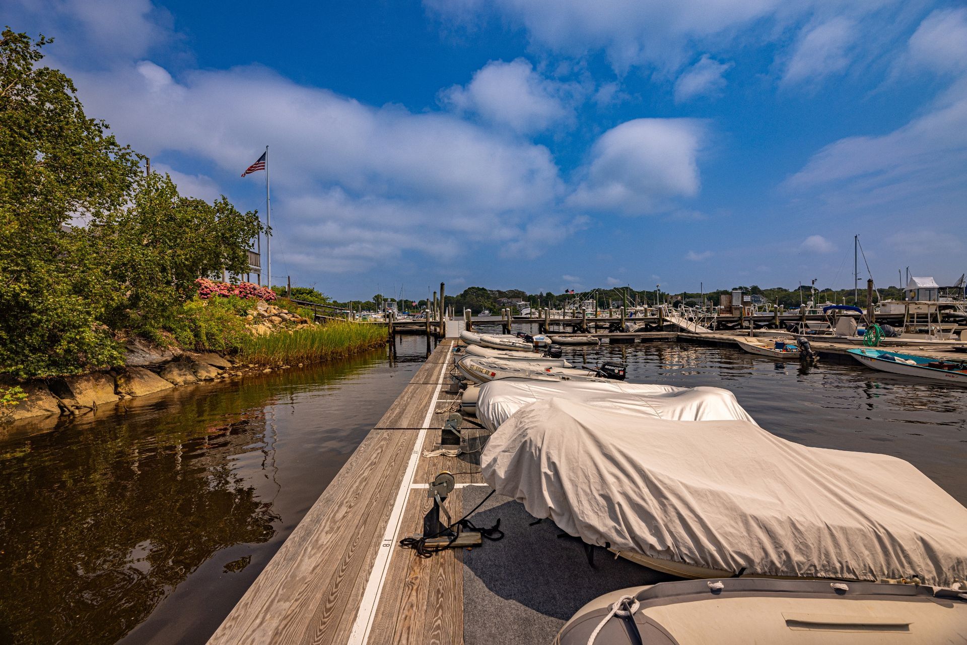 A boat with a cover on it is sitting on a dock next to a body of water.