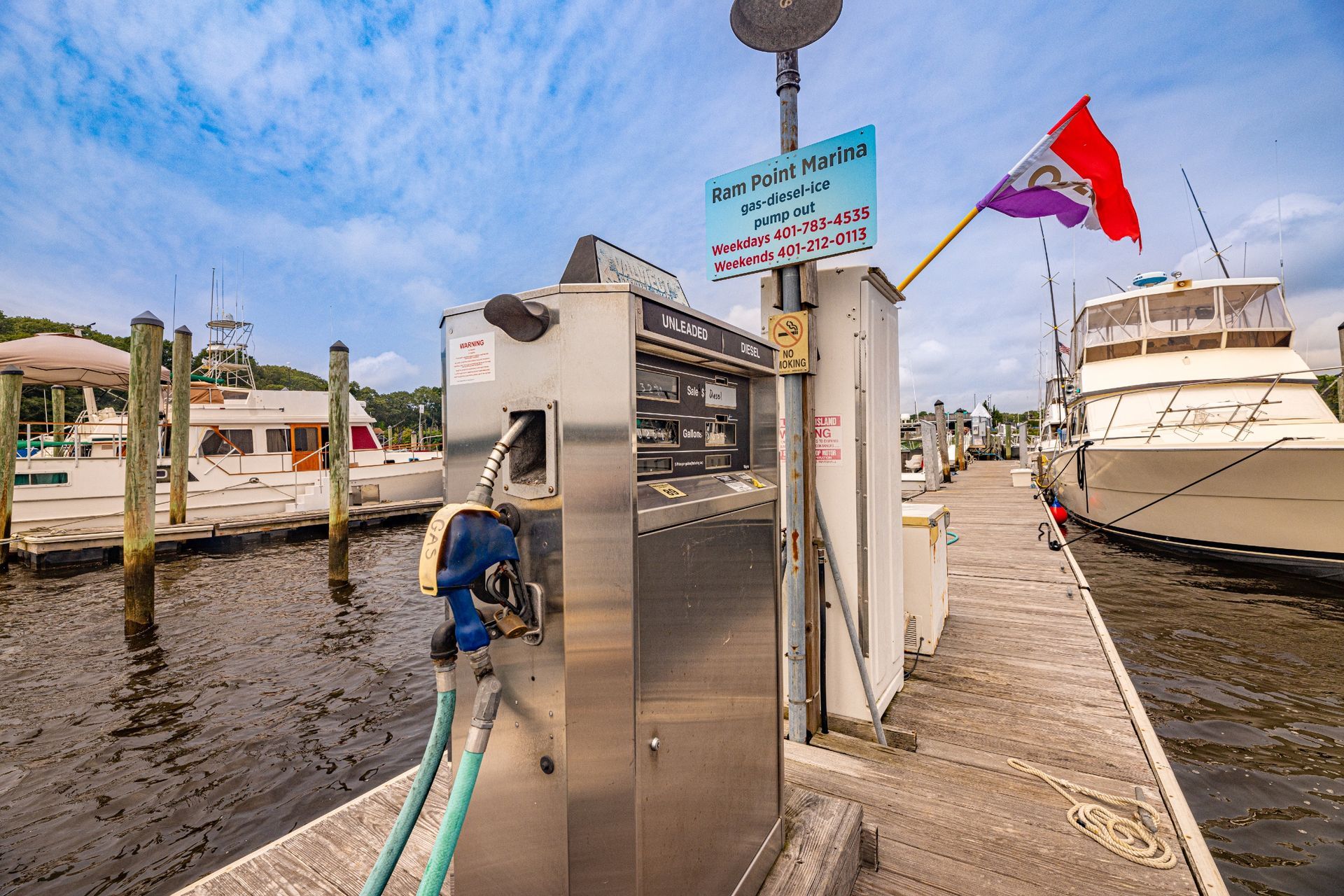 A boat is being fueled at a dock with boats in the background.