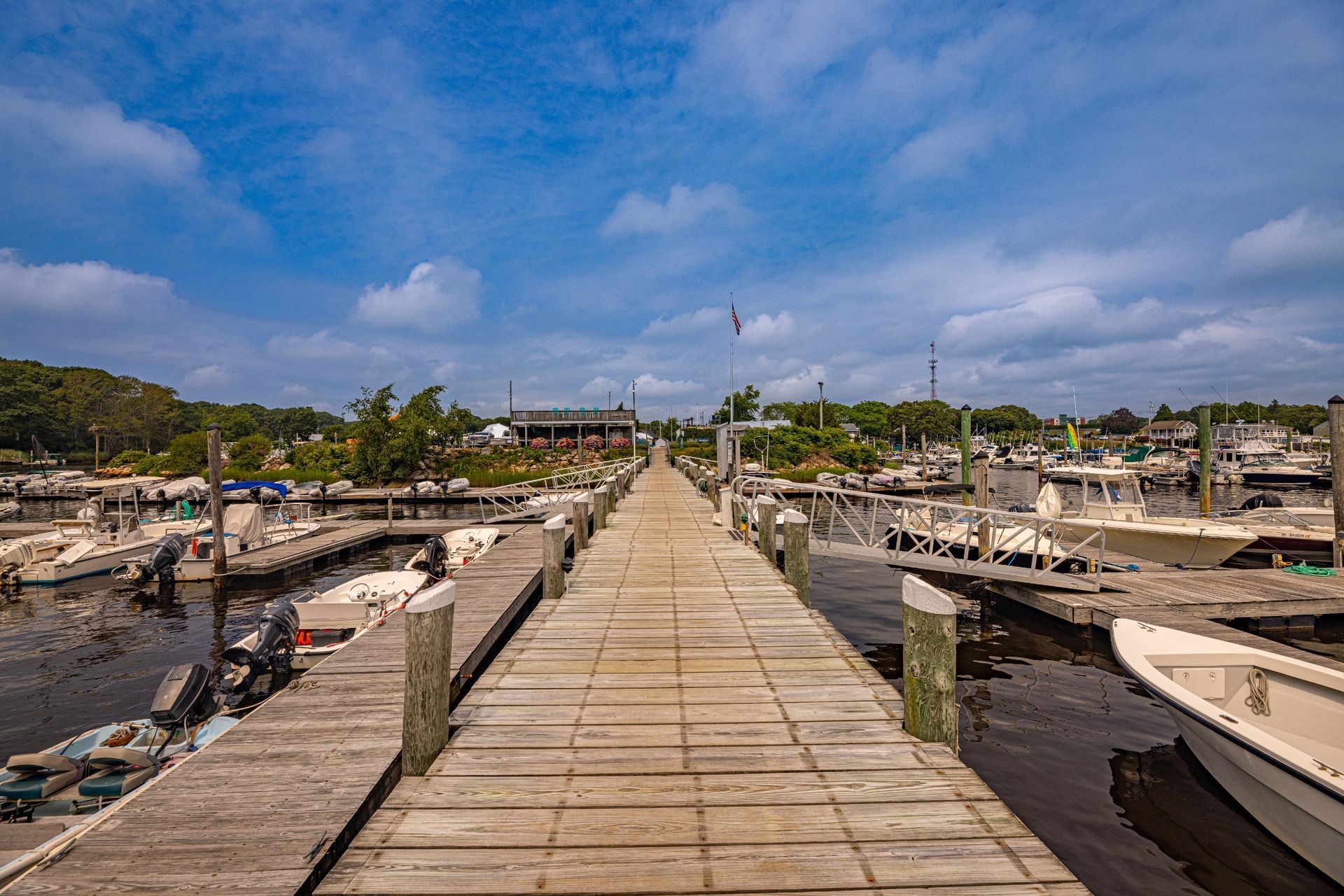 A long wooden dock leading to a marina filled with boats.