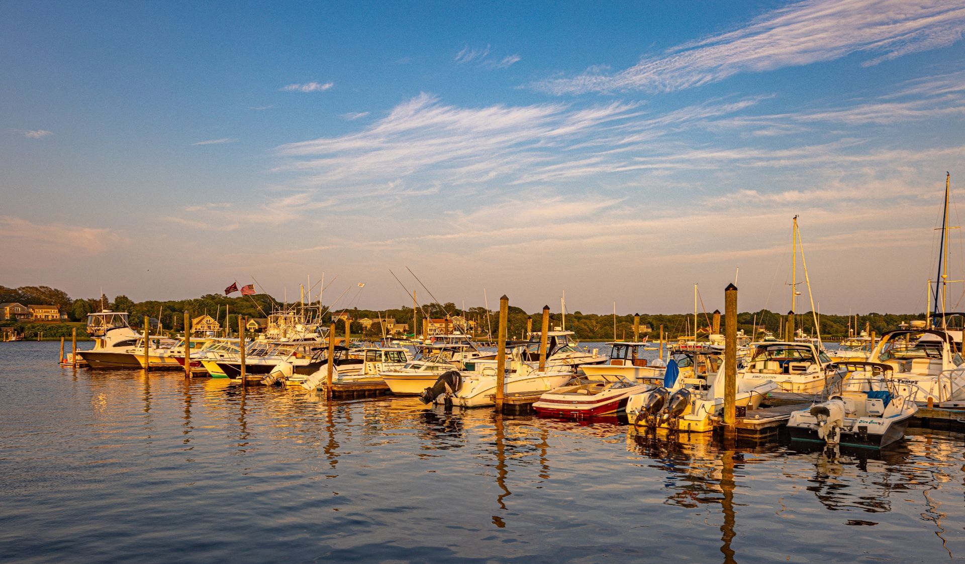 A row of boats are docked in a marina on a sunny day.