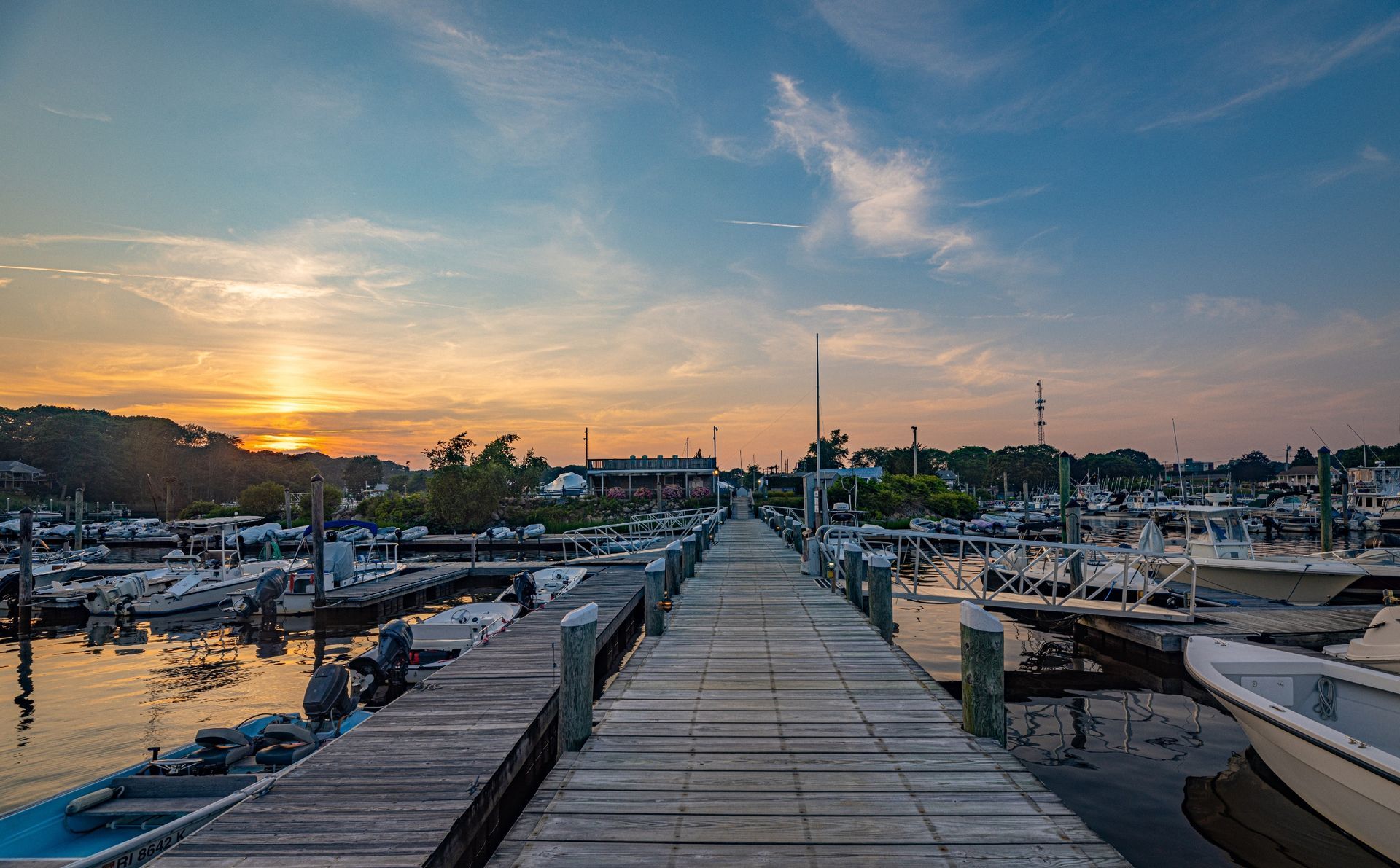 A dock with boats docked at a marina at sunset.