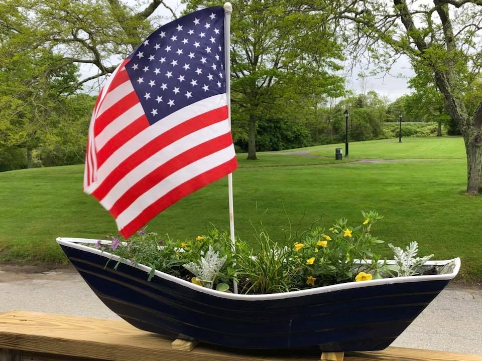 A boat planter with an american flag on top of it