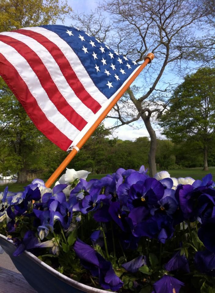 An american flag is in a pot of purple flowers
