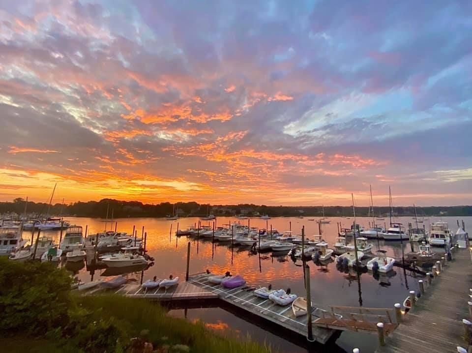 A sunset over a marina filled with boats and jet skis.