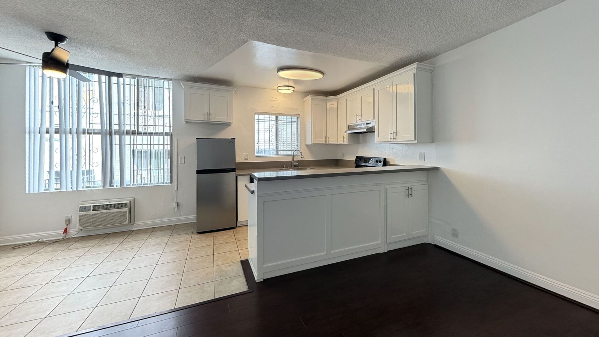 Kitchen with white cabinets, stainless steel fridge, and a dark wood floor.