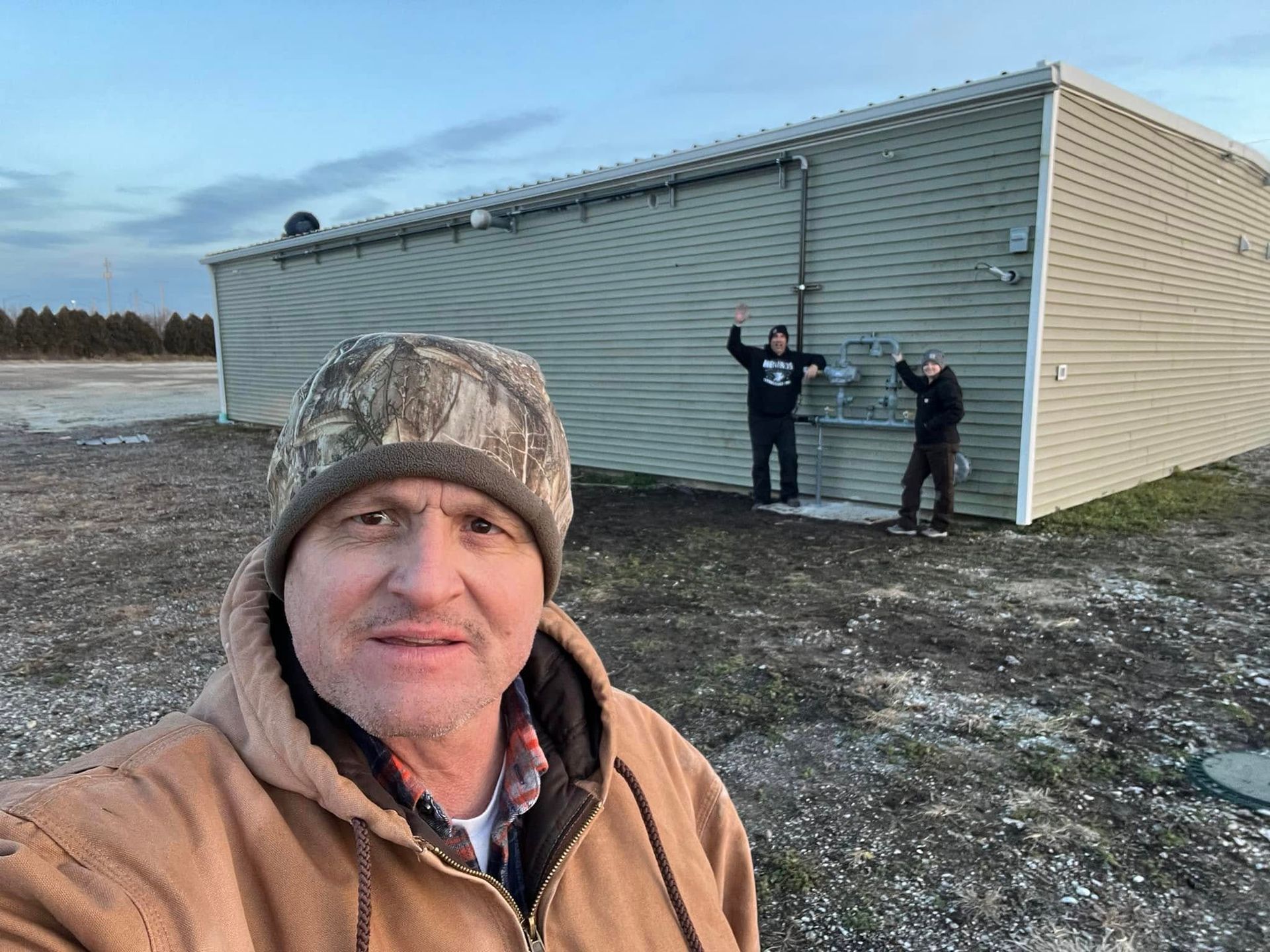 A man in a camouflage hat is standing in front of a building.