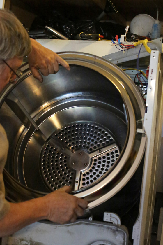 A man is working on a washer and dryer.