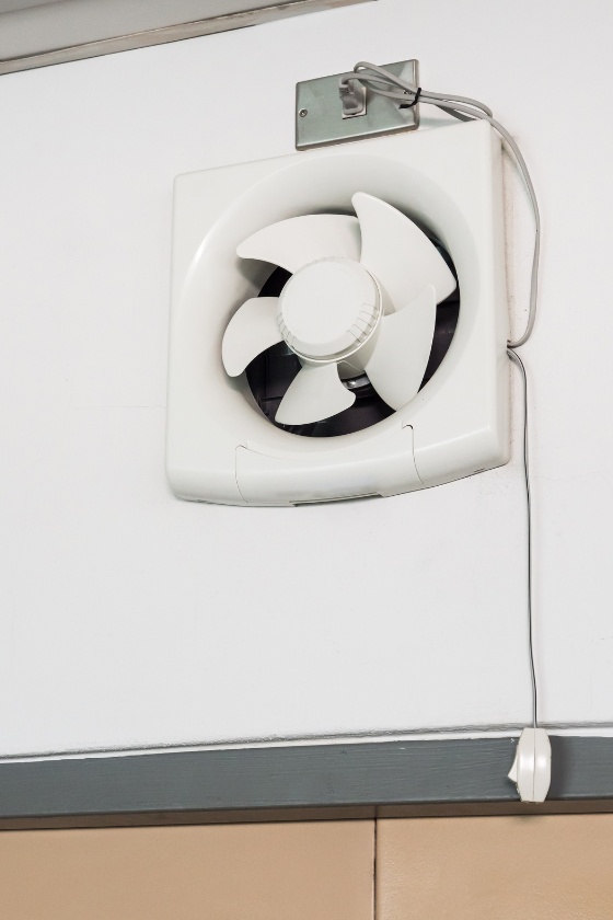 A white fan is hanging on a white wall.