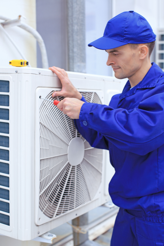 A man in a blue uniform is working on an air conditioner