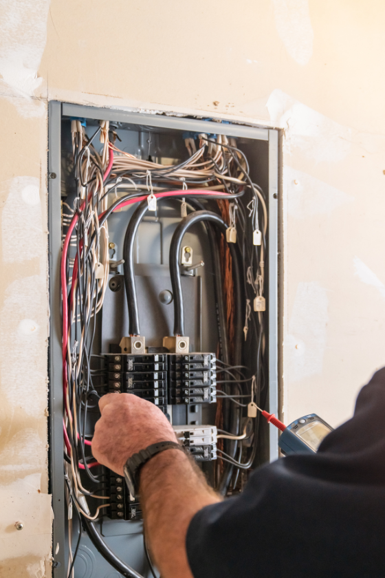 A man is working on an electrical box with a screwdriver.