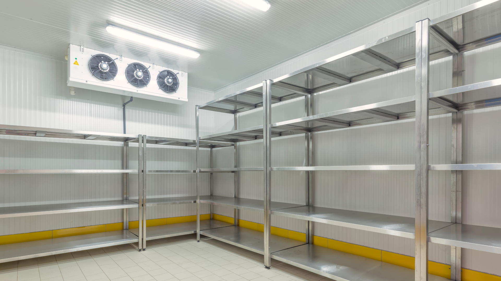 An empty refrigerator with stainless steel shelves and a fan.