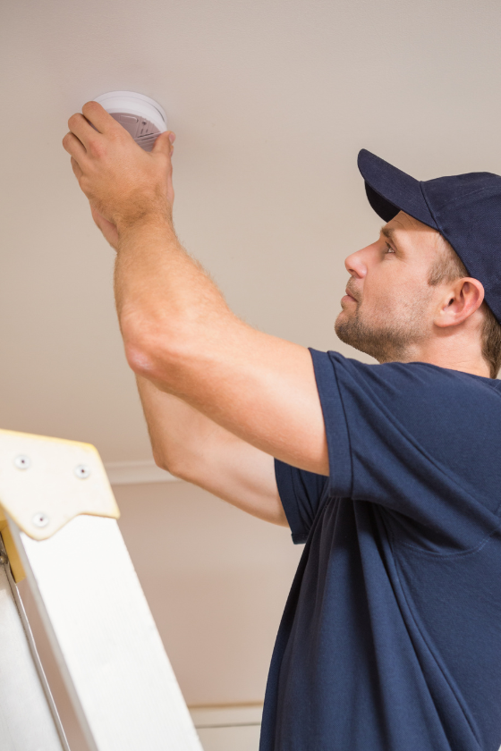 A man is standing on a ladder holding a light bulb.