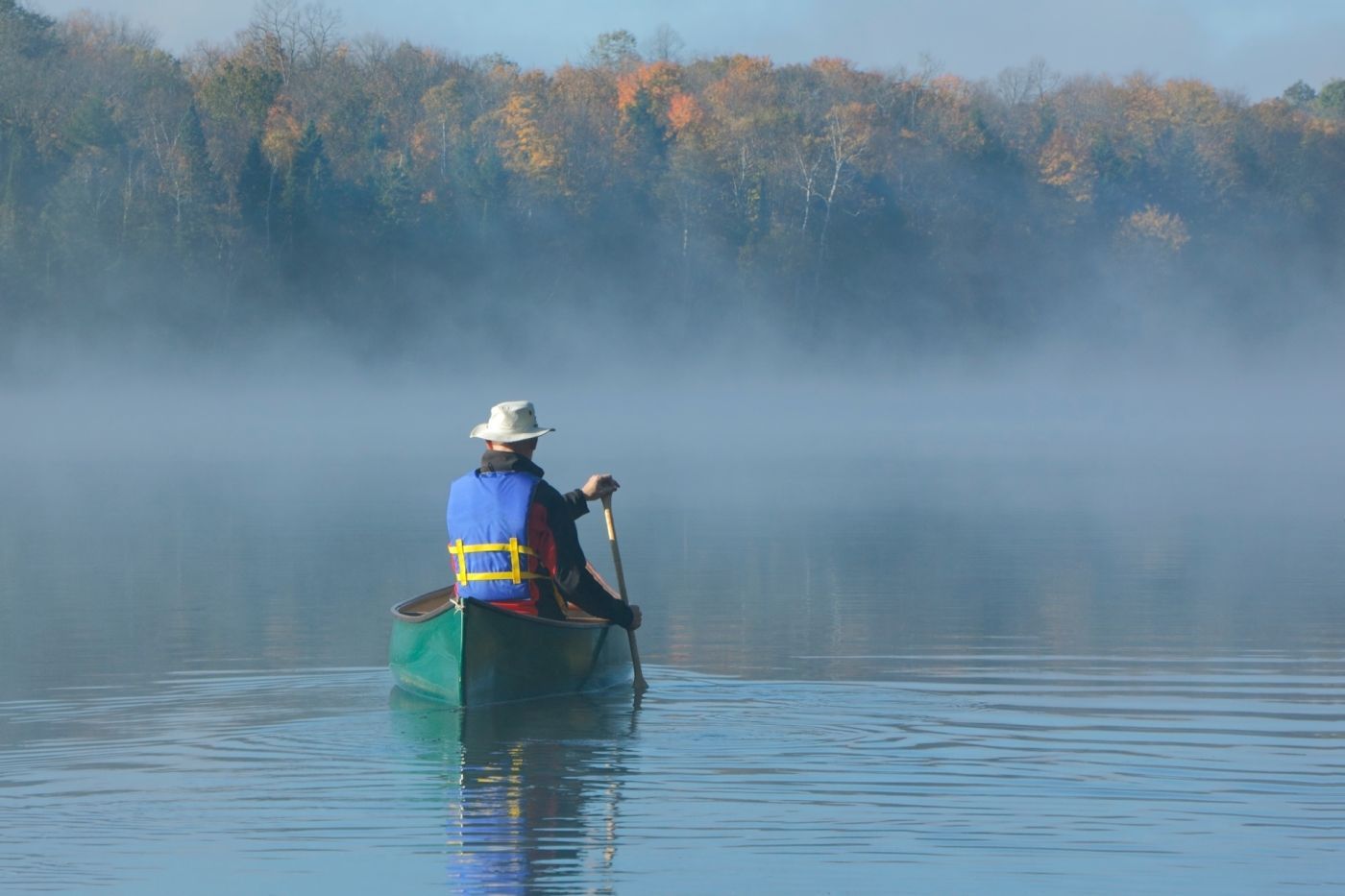 afbeelding van man in kano op meer in de mist, Oost-Canada