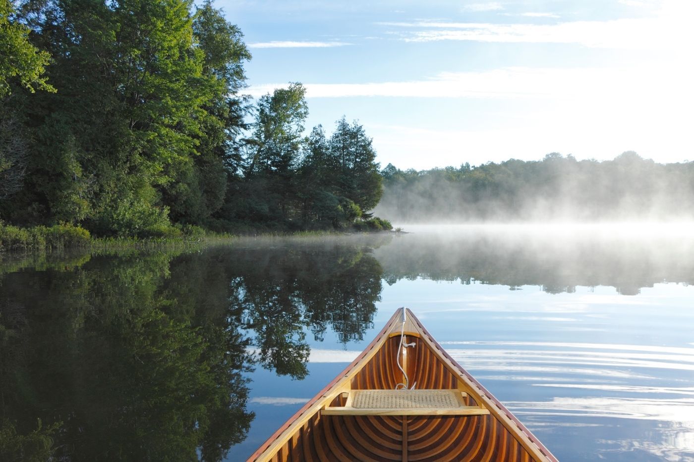 afbeelding van man in kano op meer in de mist
