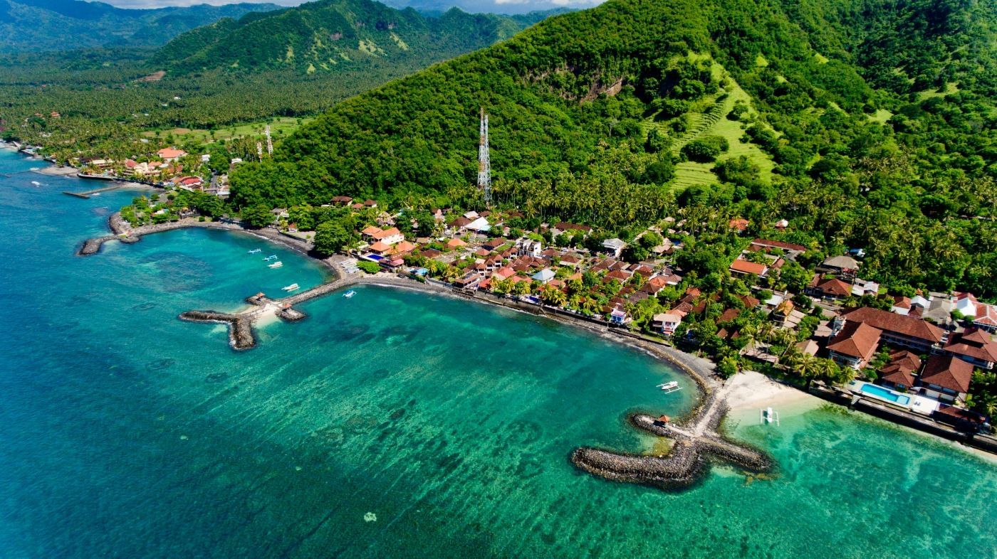 een luchtfoto van een tropisch strand met bergen op de achtergrond. Strand Bali