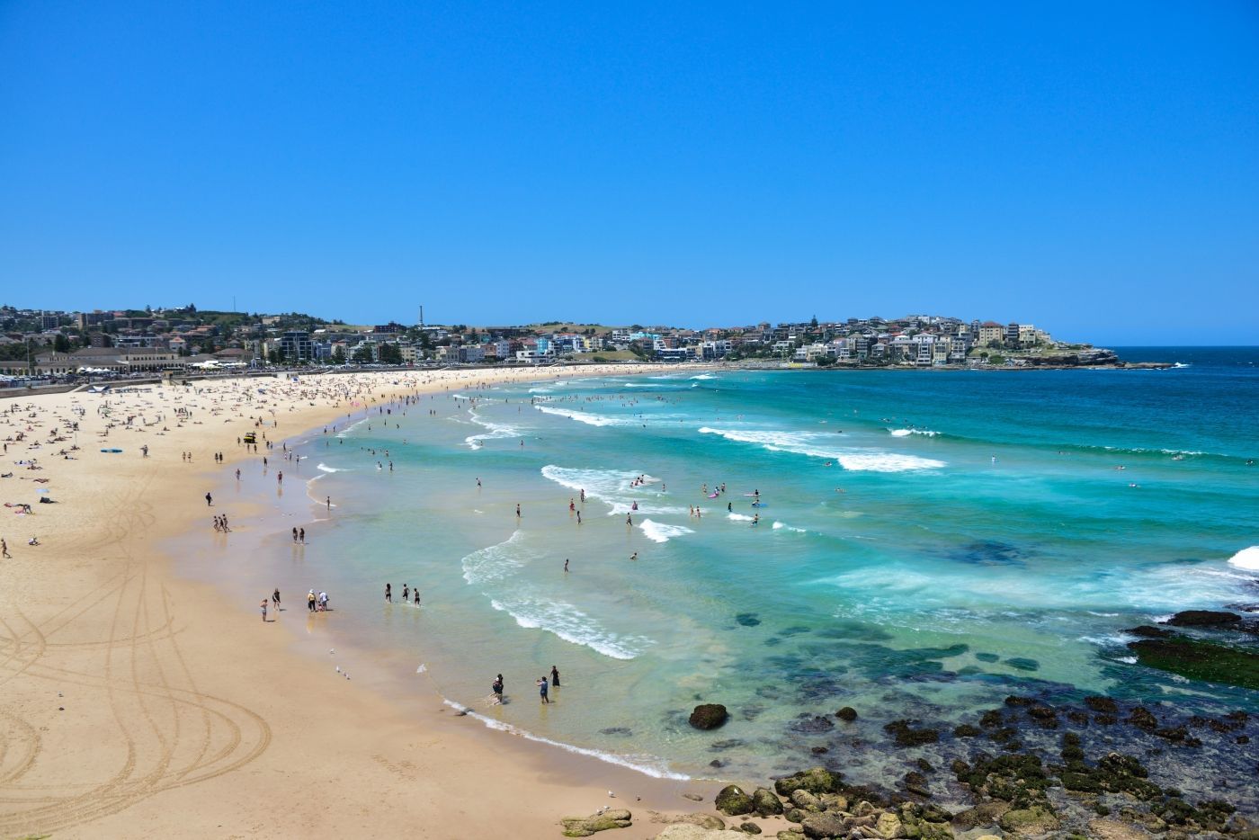 Een strand vol mensen en golven op een zonnige dag