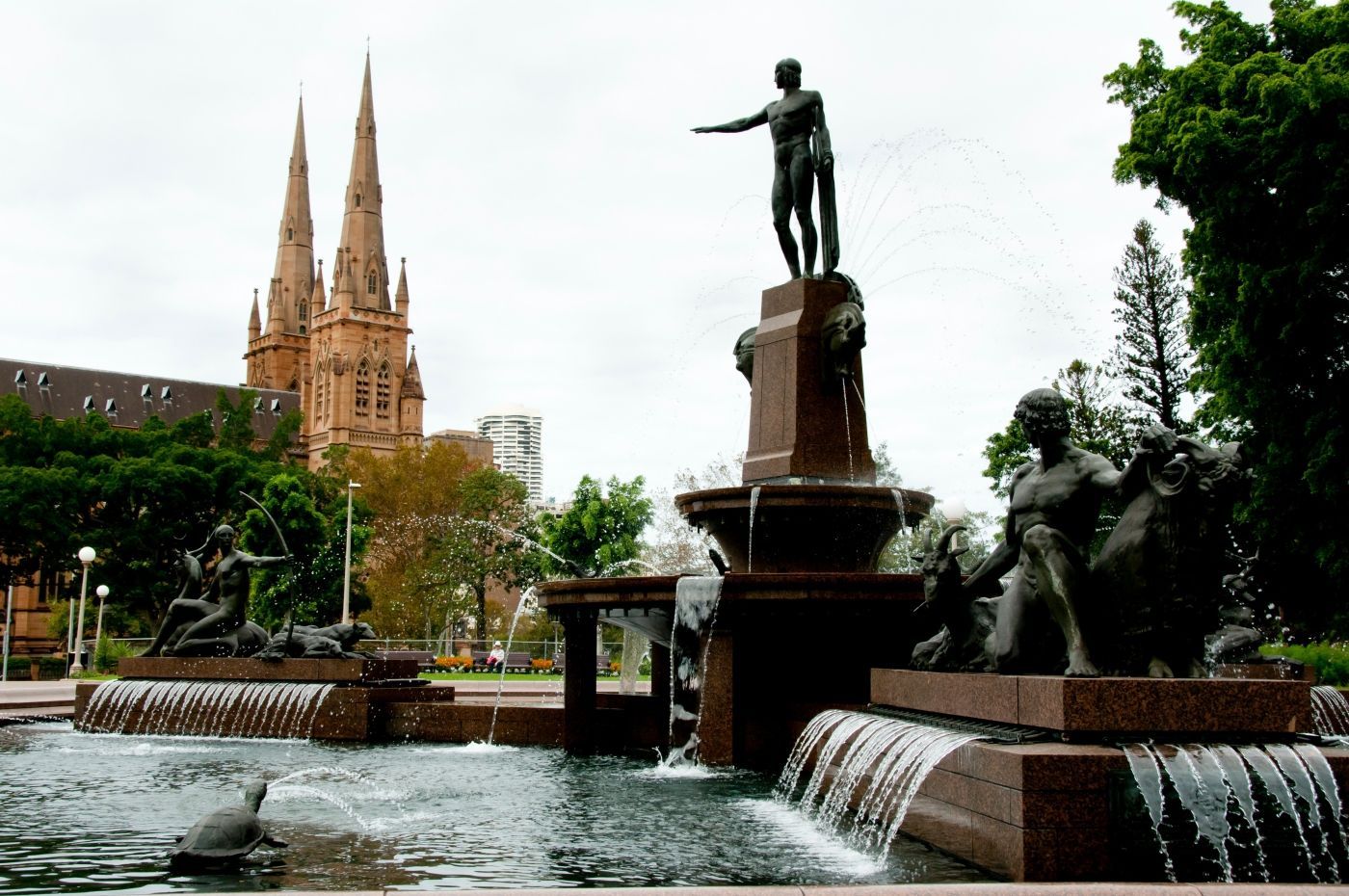 Een fontein in een park met een kathedraal op de achtergrond