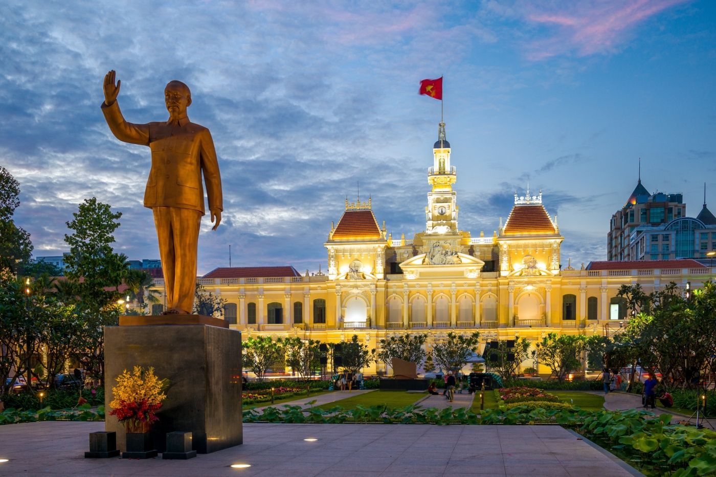 een standbeeld van een man die voor een gebouw staat met een vlag op de achtergrond. Vietnam Hoi Chi Ming