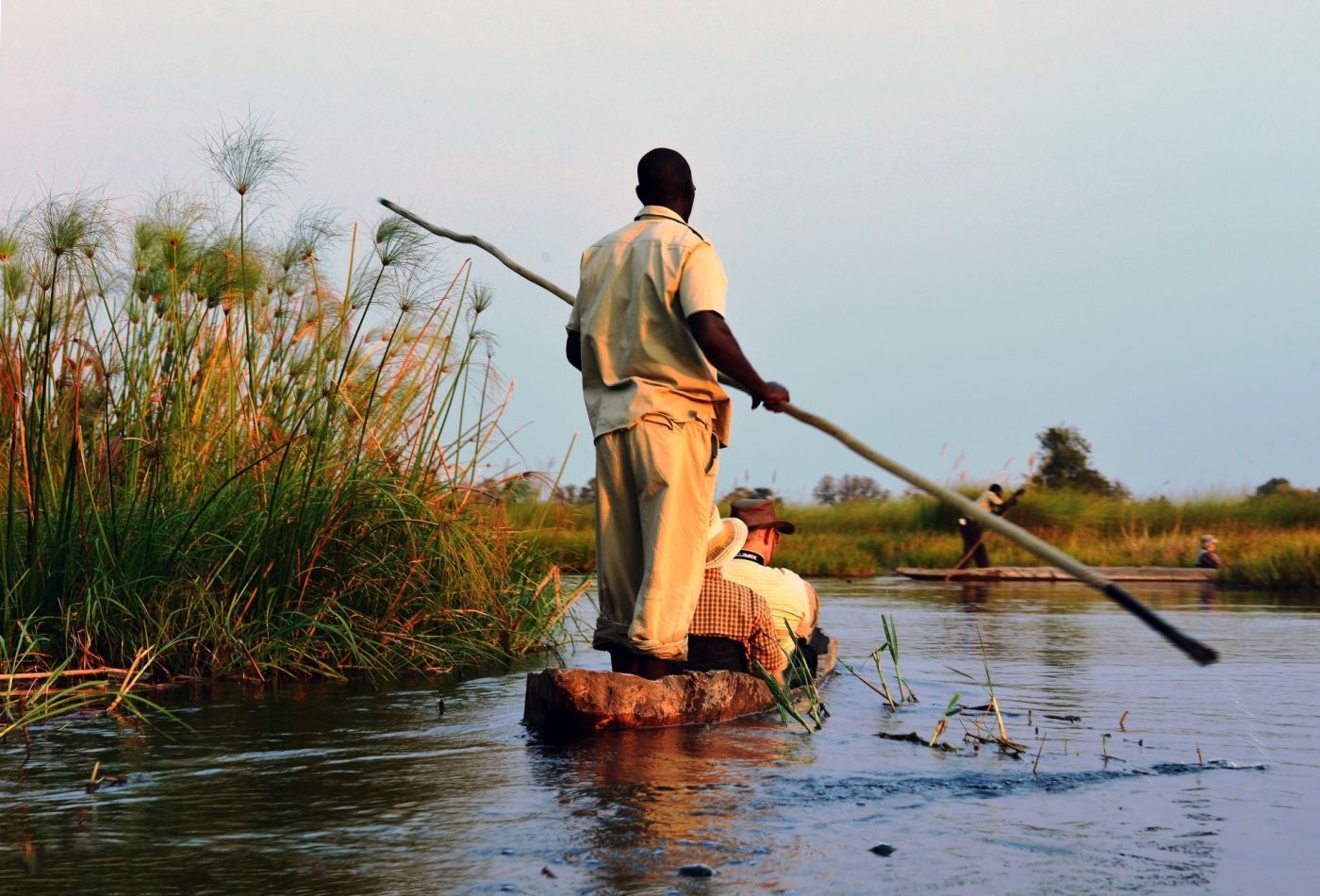 een man staat op een boomstam in het water en houdt een peddel vast