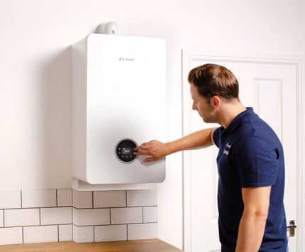 A man is adjusting a boiler in a kitchen.