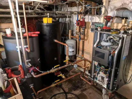 A room with a lot of pipes and a water heater.