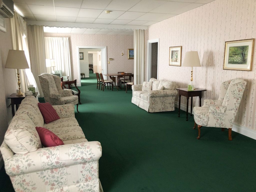 A living room with a couch , chairs , tables and lamps.