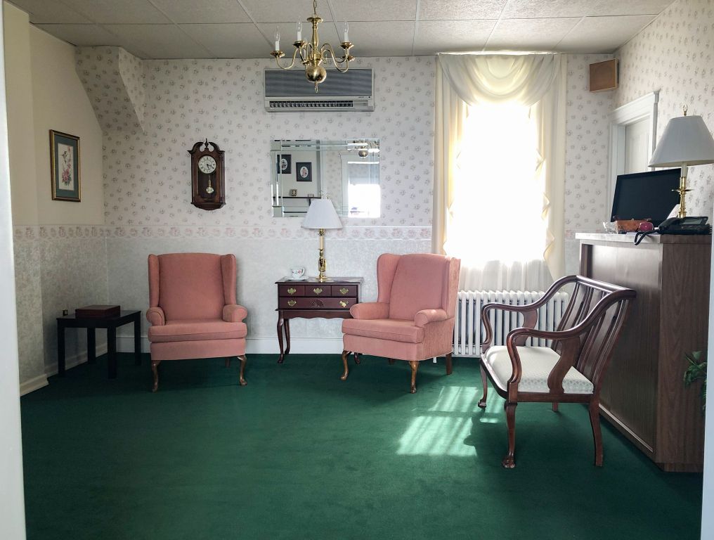 A living room with pink chairs and a green carpet