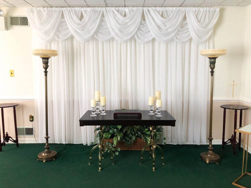 A room with a table and candles in front of a white curtain