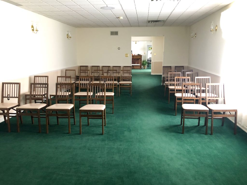 A row of chairs are lined up in a room with green carpet.