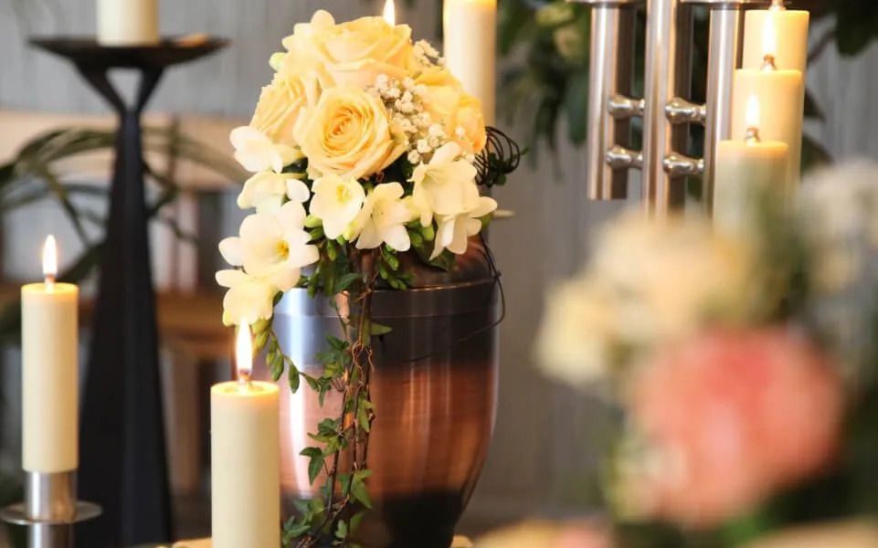 A vase filled with flowers and candles on a table.