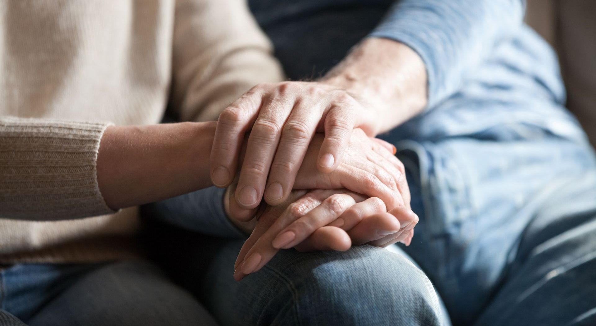 A woman is holding a man 's hand while sitting on a couch.