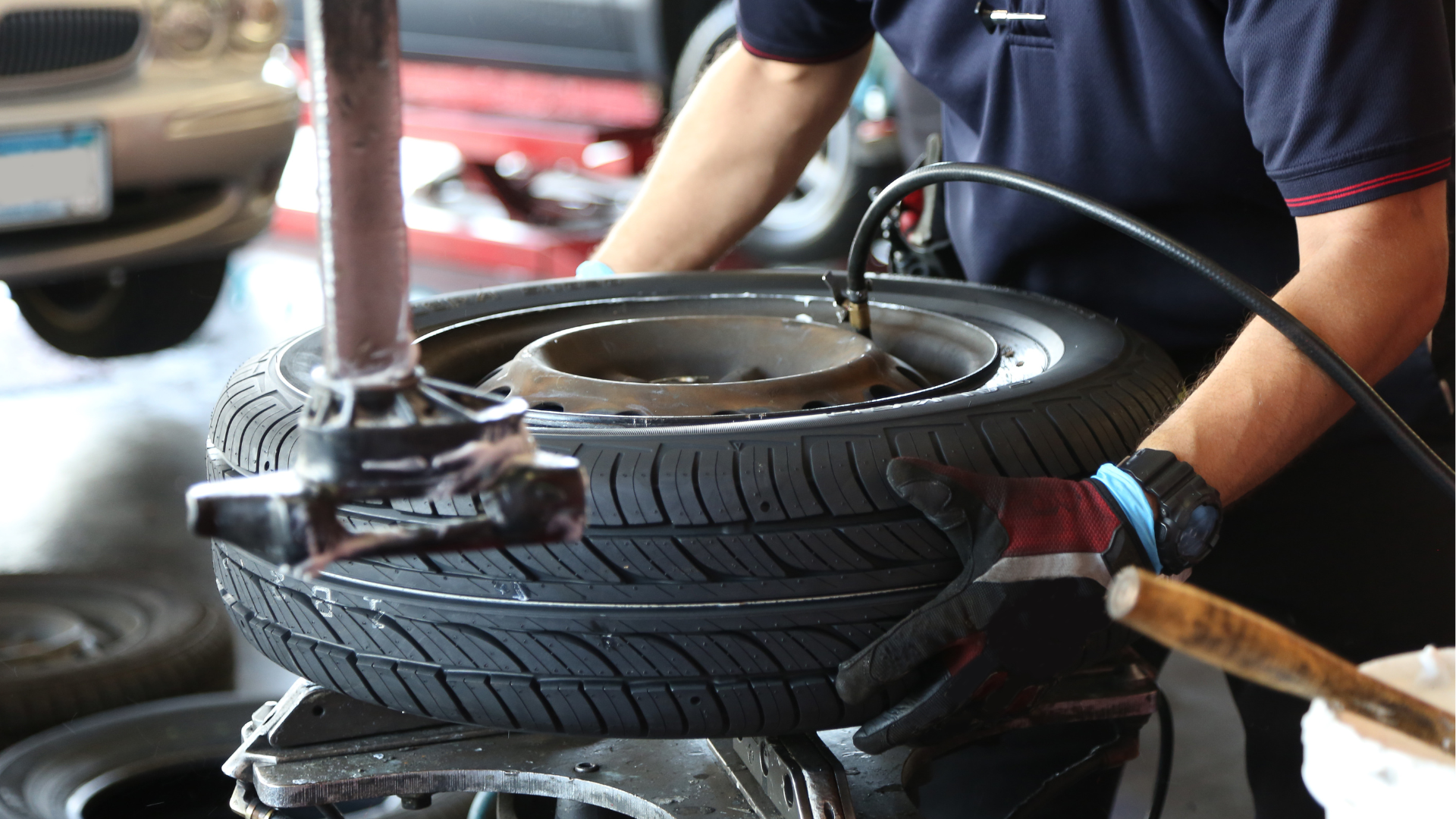 A man is changing a tire on a machine in a garage.