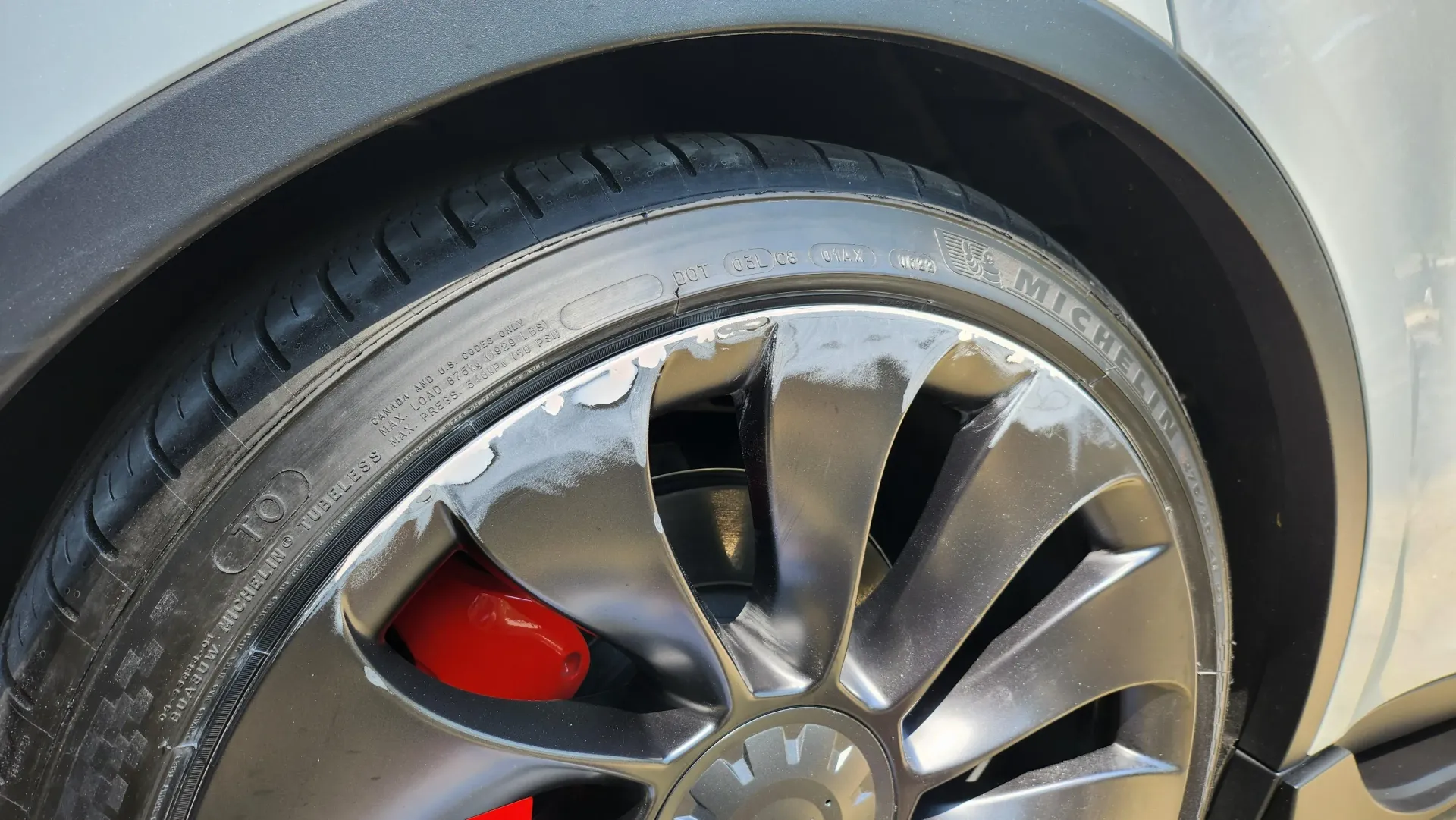 A close up of a tire on a car with red brake calipers.
