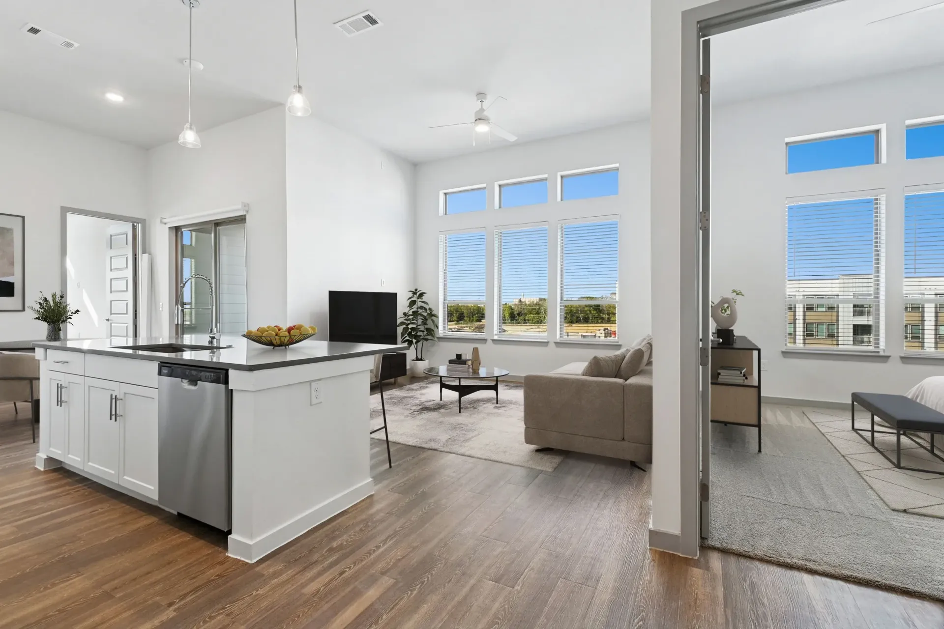 Bright open-concept kitchen and living area with white cabinets, island, and large windows.