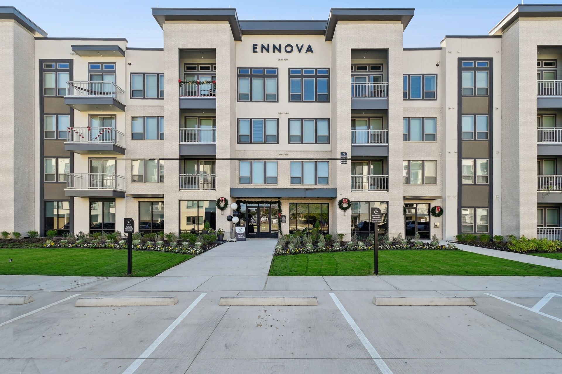 Exterior view of ENNOVA apartment building with balconies and landscaped entrance.