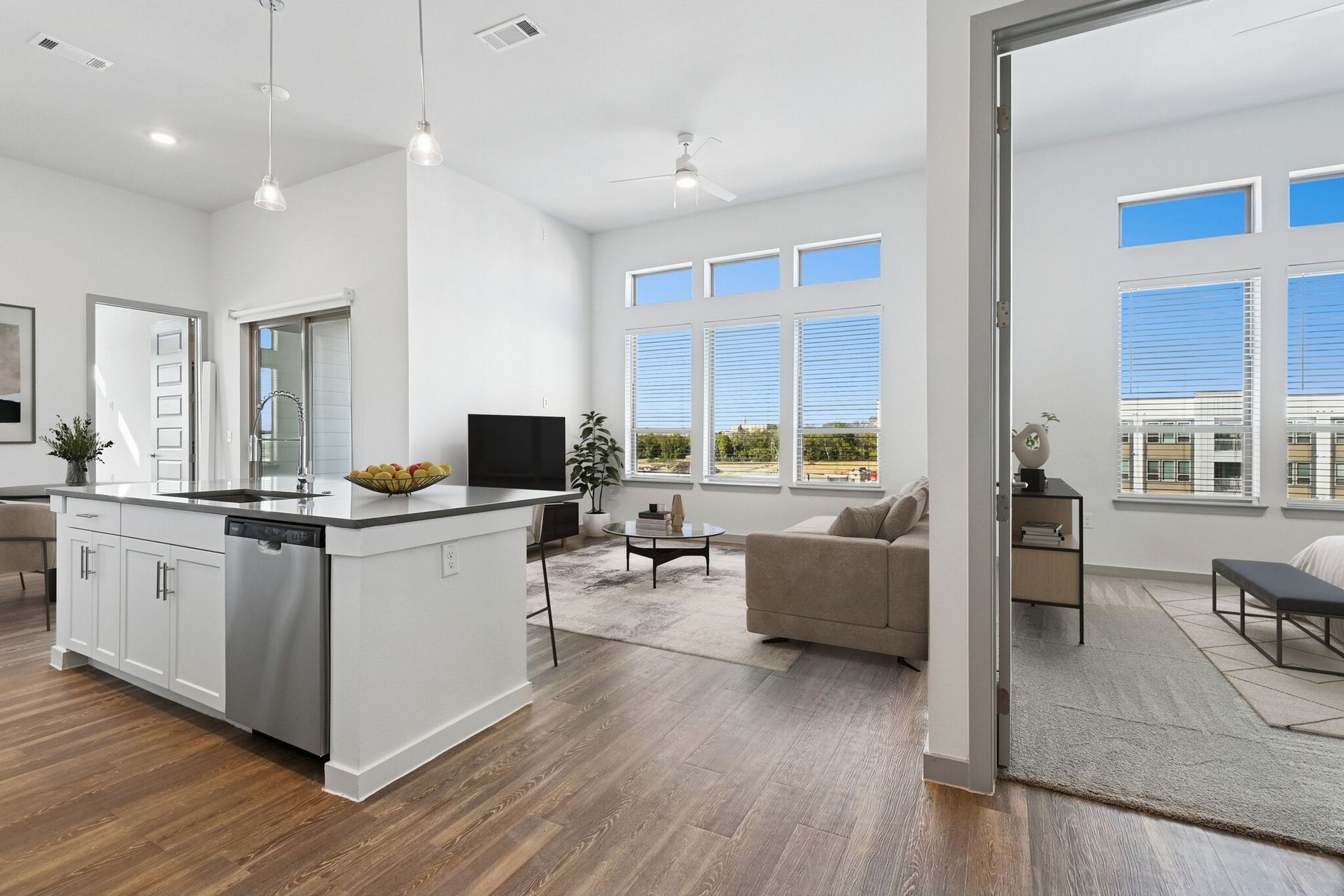 Open-concept kitchen and living area with an island, hardwood floors, and large windows.