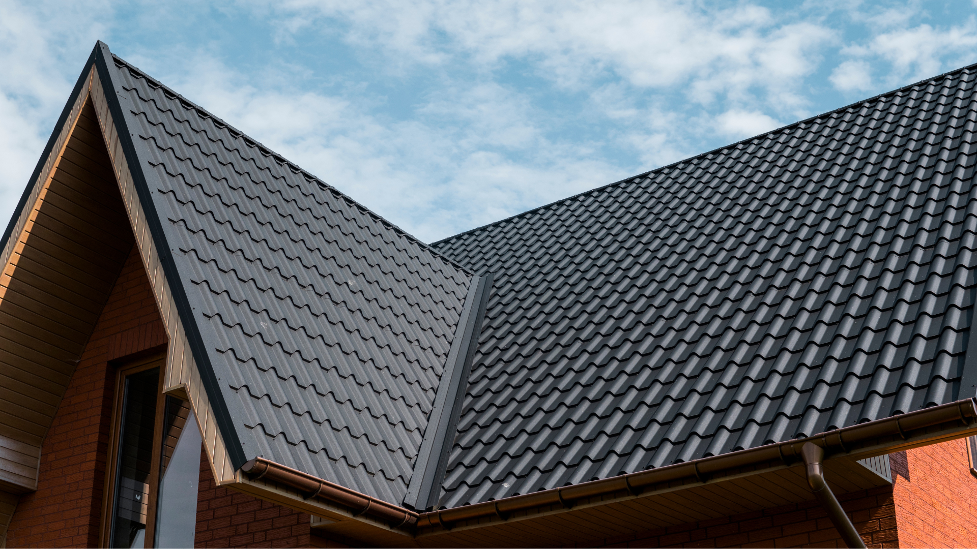 Dark gray shingled roof with a steep gable against a blue sky