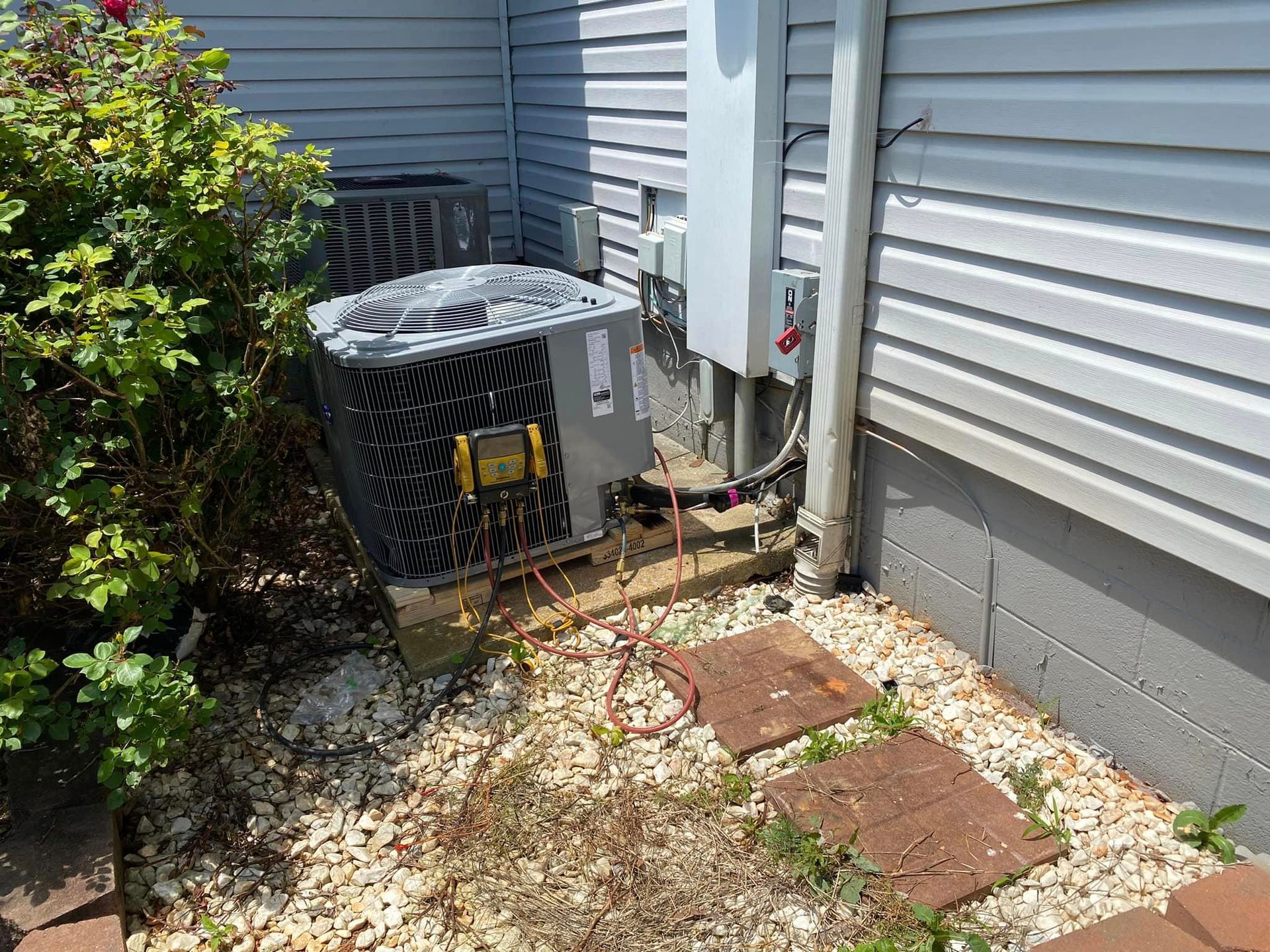 An air conditioner is sitting on the side of a house.