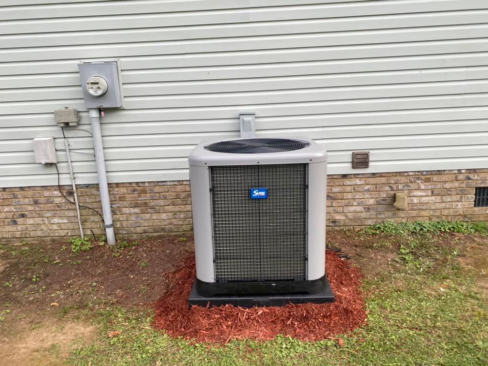 An air conditioner is sitting on the side of a house.