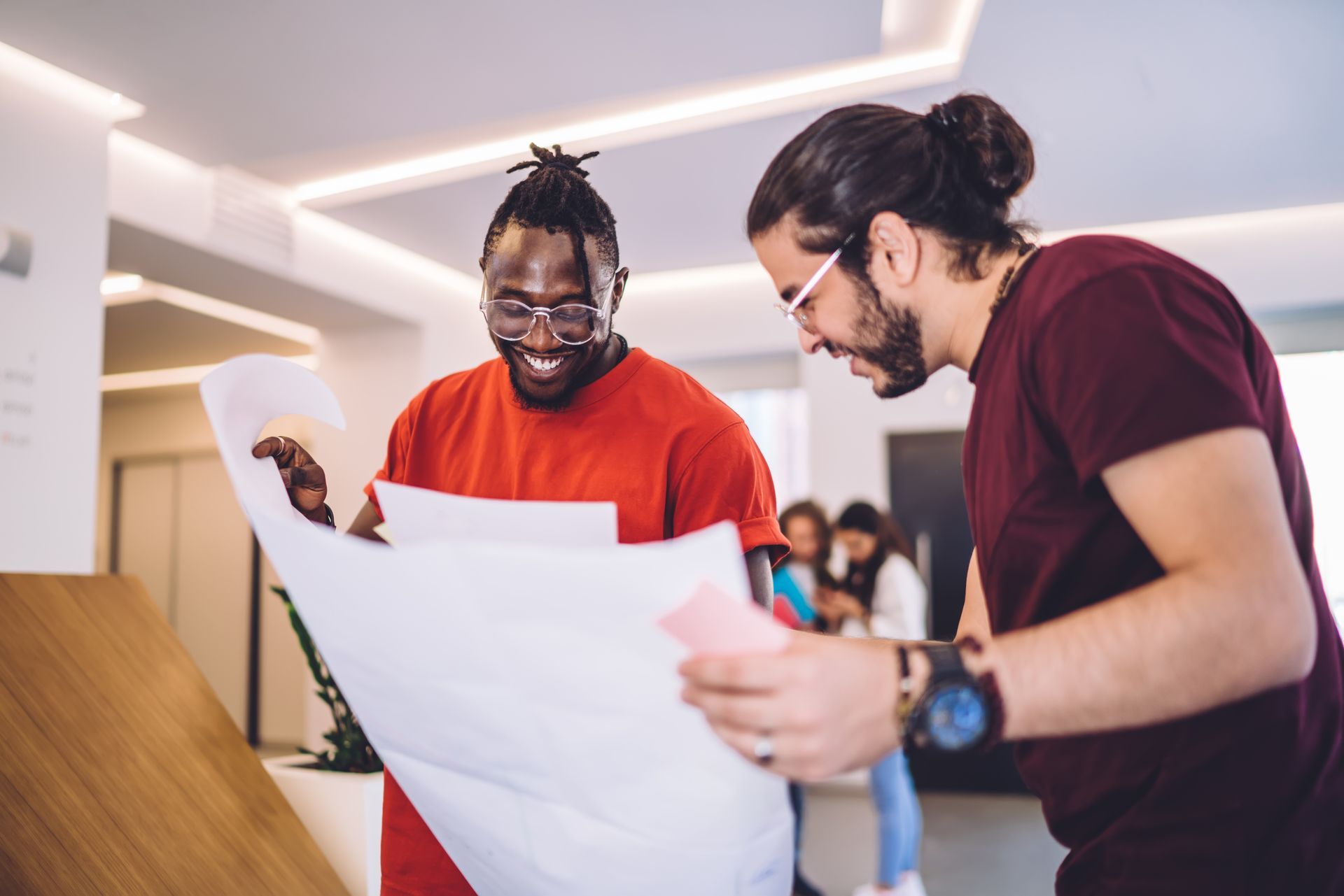 Two men are looking at a blueprint together in an office.