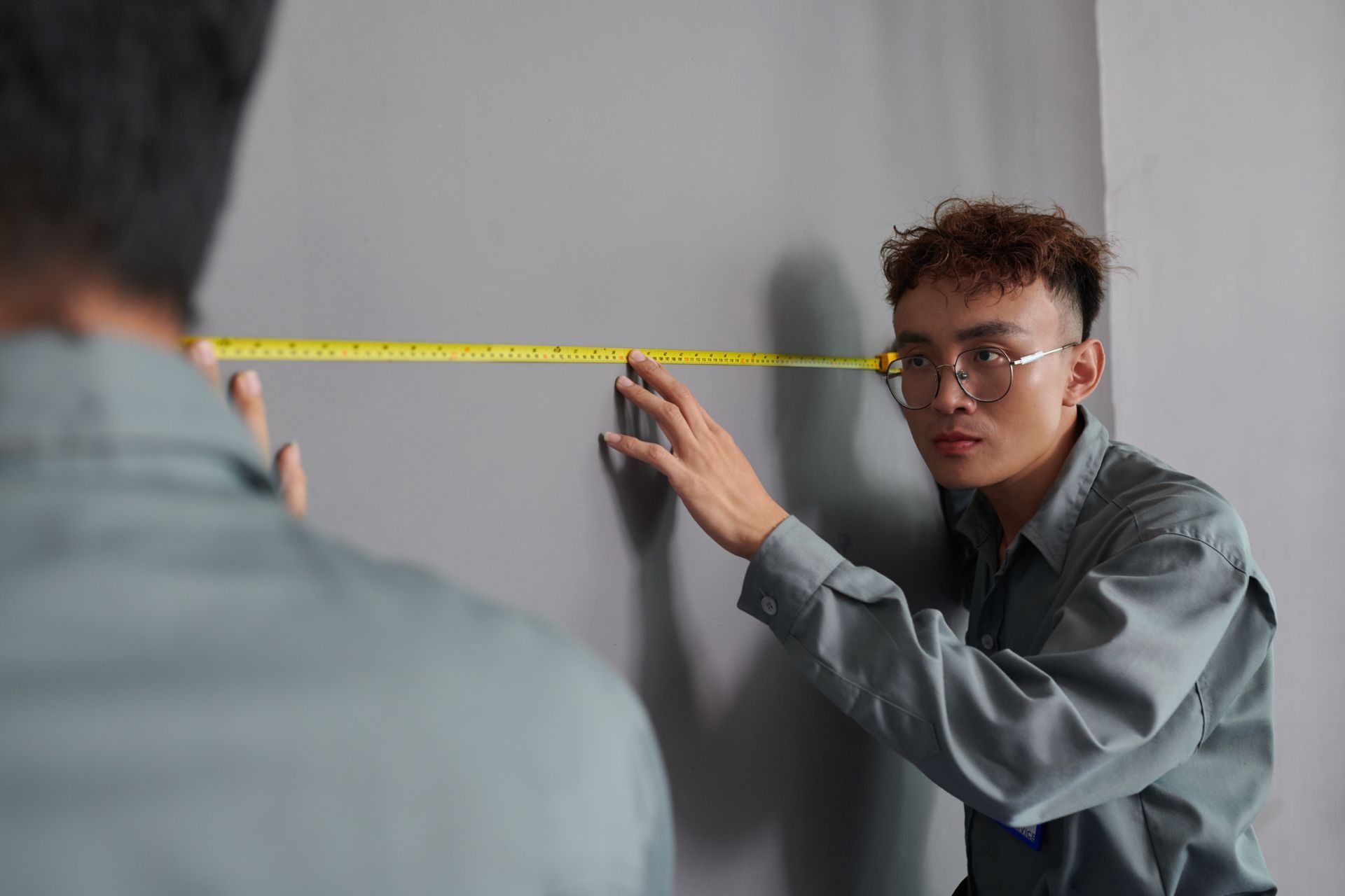 A man is measuring a wall with a tape measure.