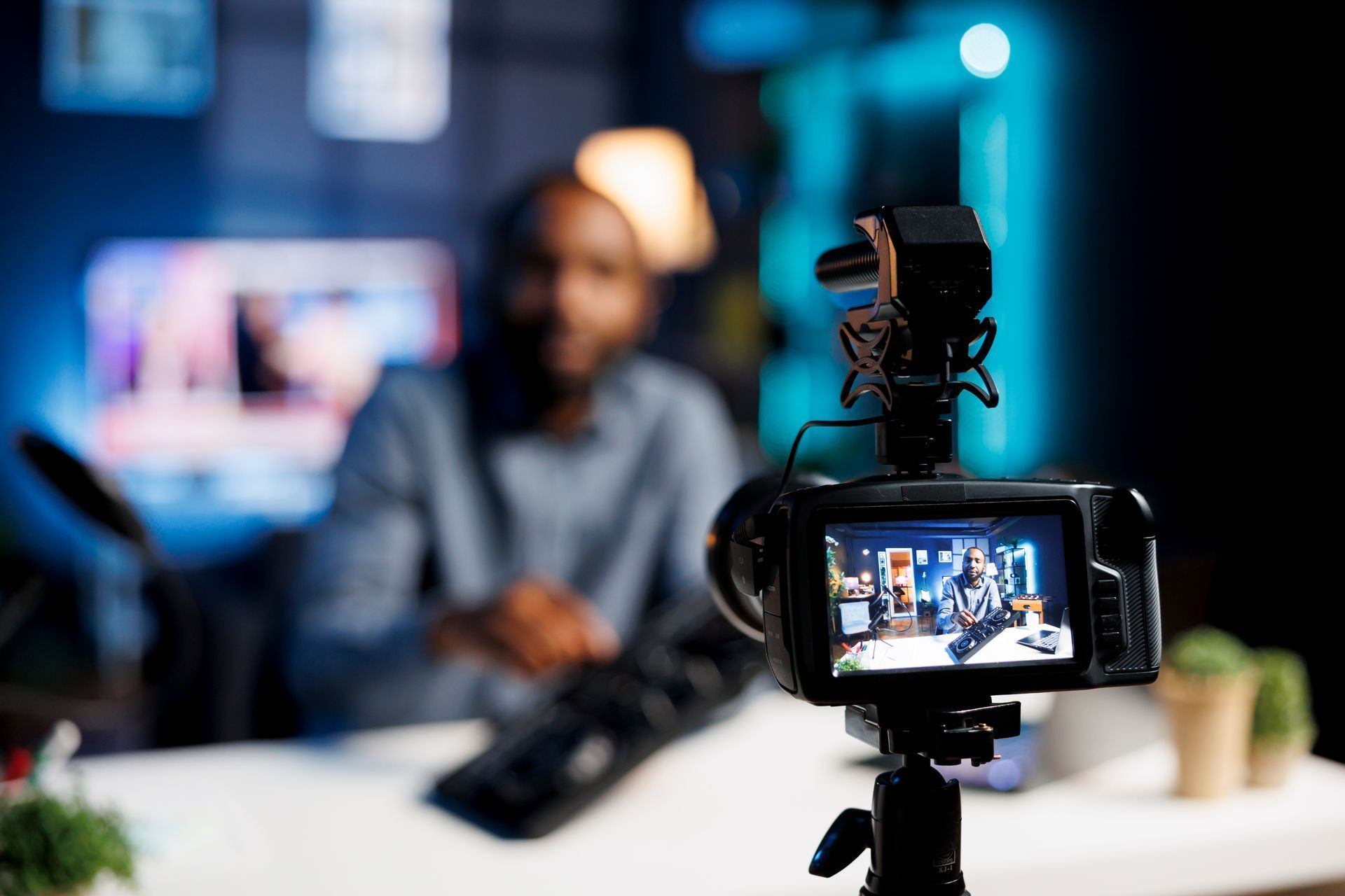 A man is sitting at a table in front of a camera.