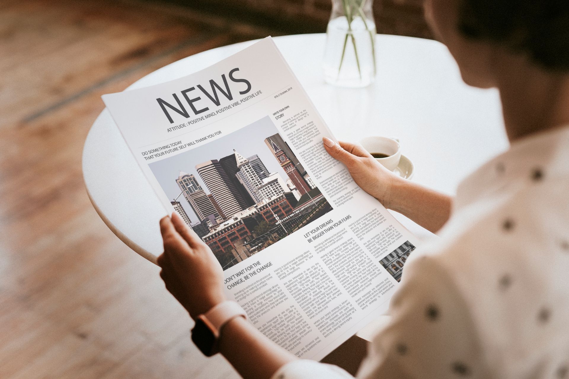 A woman is sitting at a table reading a newspaper.