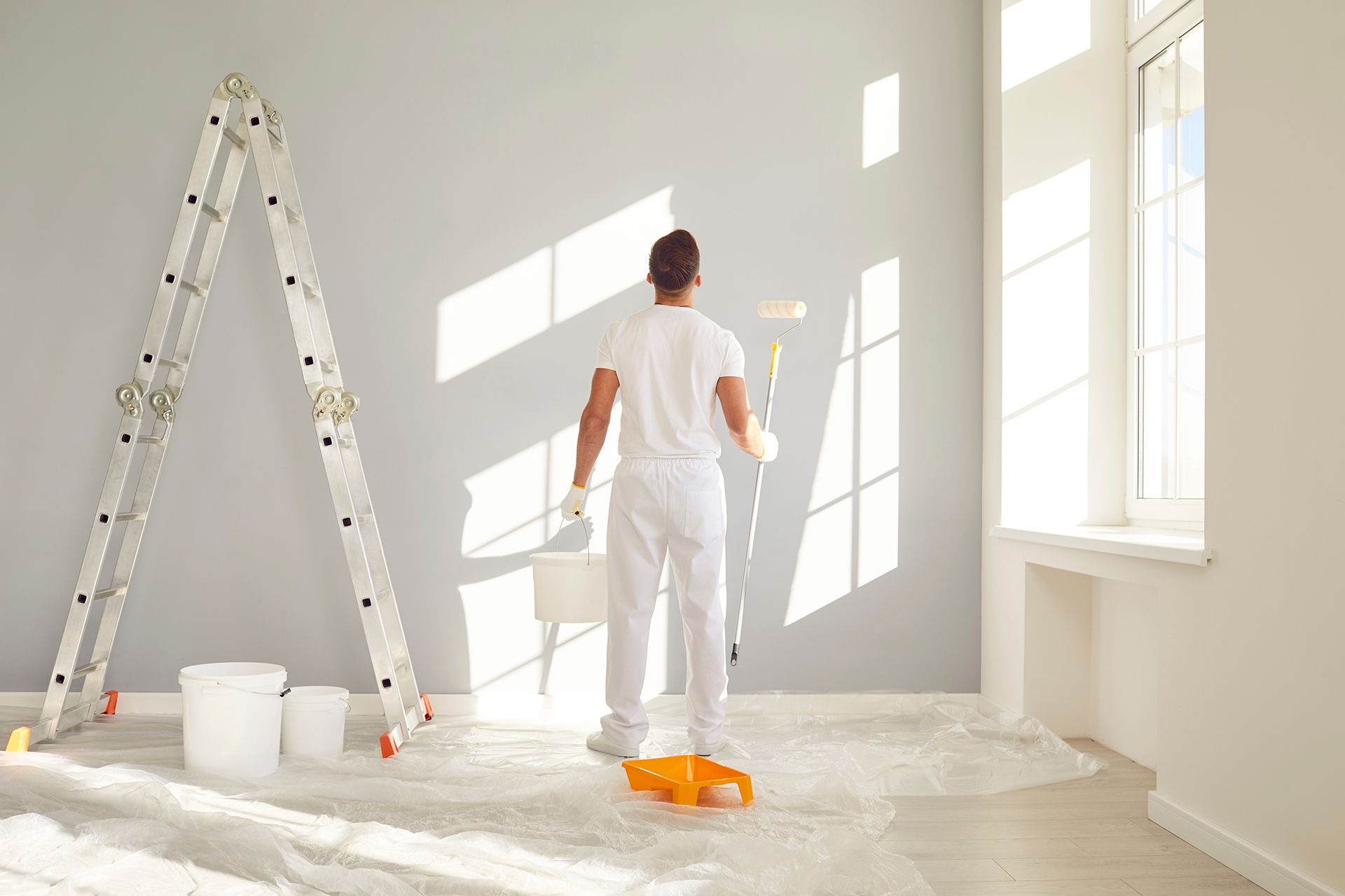 A man is painting a wall in an empty room.